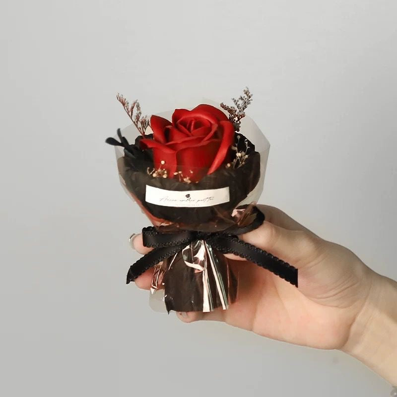 A series of four mini pocket rose bouquets in clear plastic boxes, each with a different color rose, displayed on a dark surface.