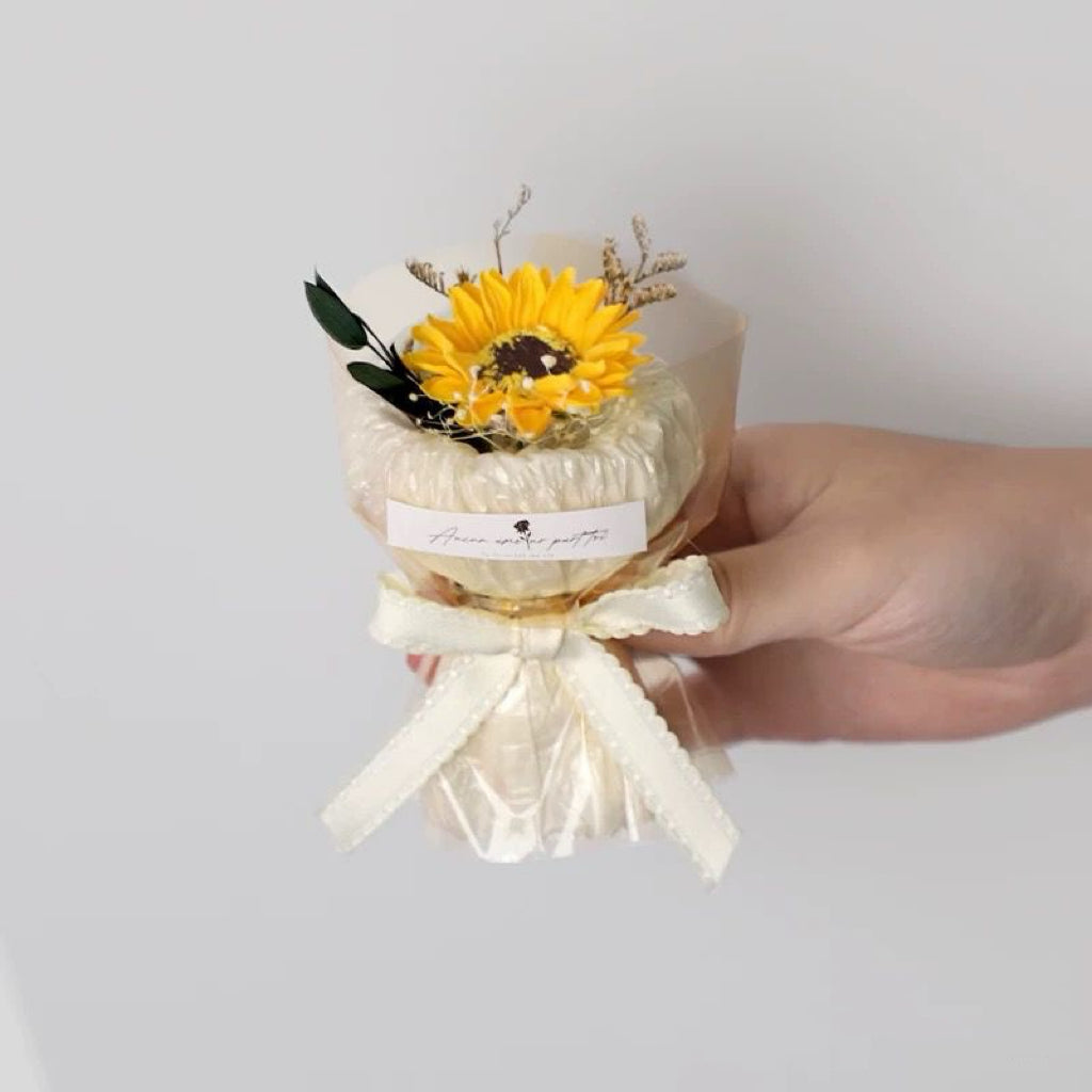A series of four mini pocket rose bouquets in clear plastic boxes, each with a different color rose, displayed on a dark surface.