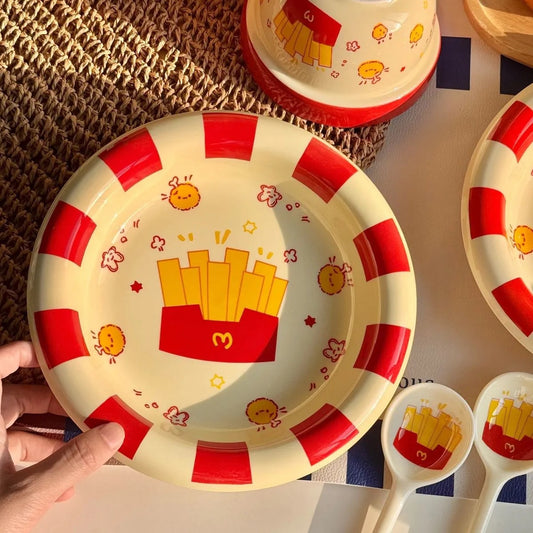 Children's plate with red stripes and French fry design, held by a hand.