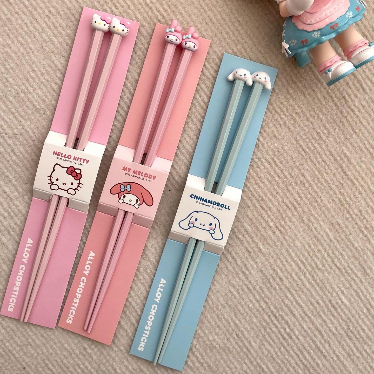 Set of chopsticks with packaging featuring Hello Kitty, My Melody, and Cinnamoroll on a beige surface.