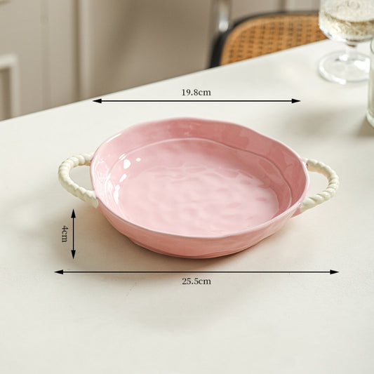 Pink ceramic dish with handles on a white surface, showing measurements.