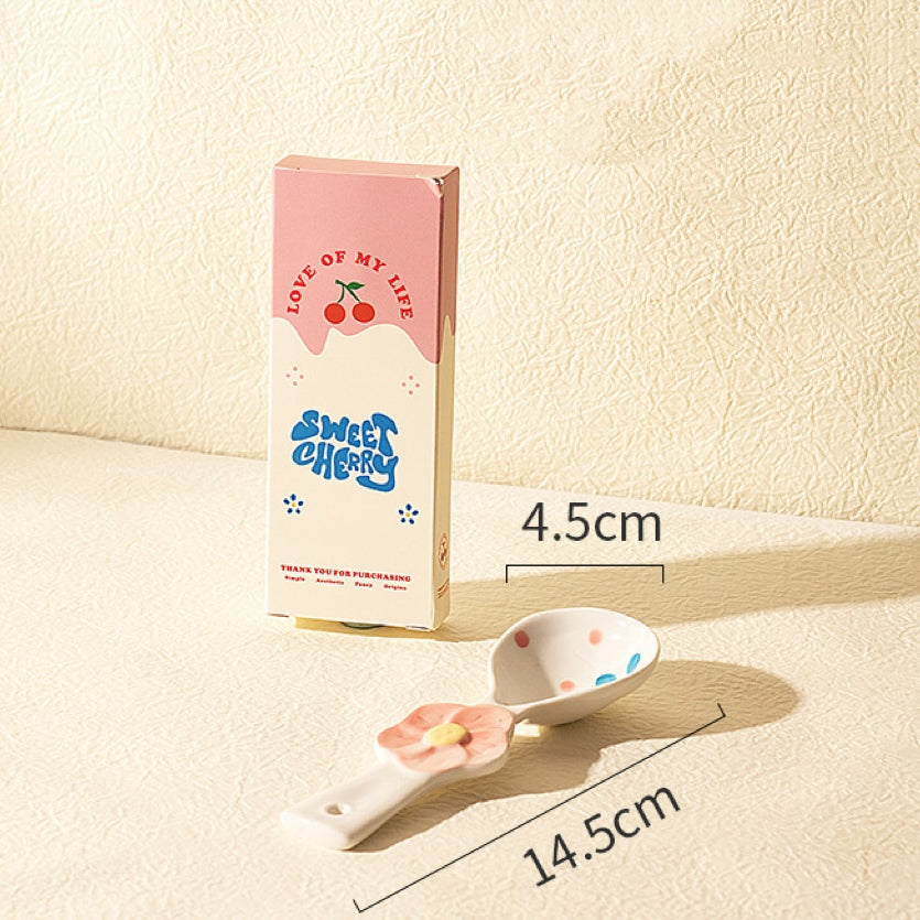 Small spoon with floral design next to a packaging box labeled 'Sweet Cherry' on a beige background.