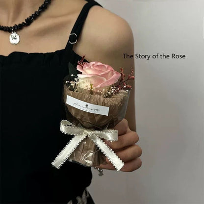 A series of four mini pocket rose bouquets in clear plastic boxes, each with a different color rose, displayed on a dark surface.