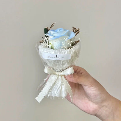 A series of four mini pocket rose bouquets in clear plastic boxes, each with a different color rose, displayed on a dark surface.