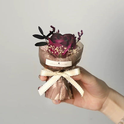 A series of four mini pocket rose bouquets in clear plastic boxes, each with a different color rose, displayed on a dark surface.