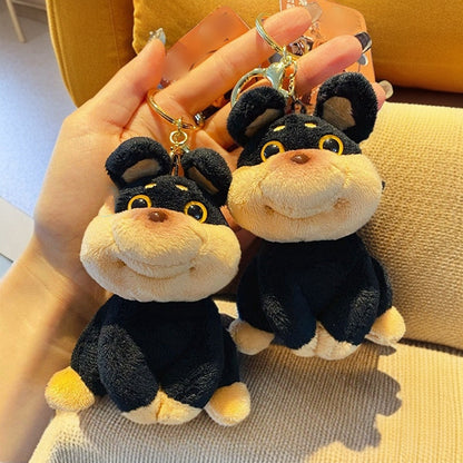 Two plush monkey keychains held by a hand on a textured surface.