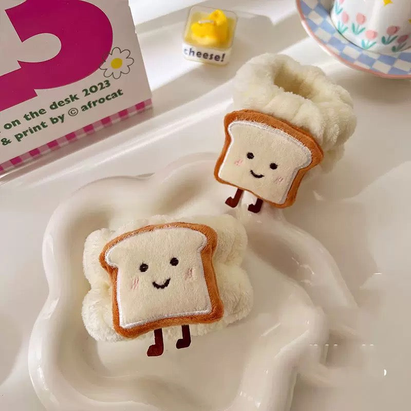 A collection of plush wrist water absorbers designed to look like toast and rice balls, in various colors, being worn on a person's wrist.