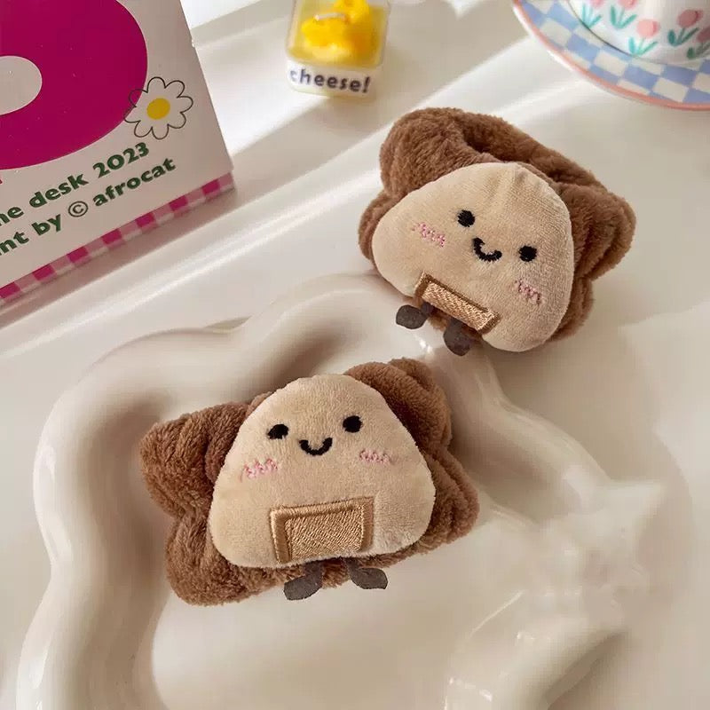 A collection of plush wrist water absorbers designed to look like toast and rice balls, in various colors, being worn on a person's wrist.