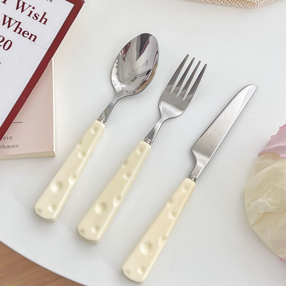 Set of silver cutlery with cream handles on a white surface