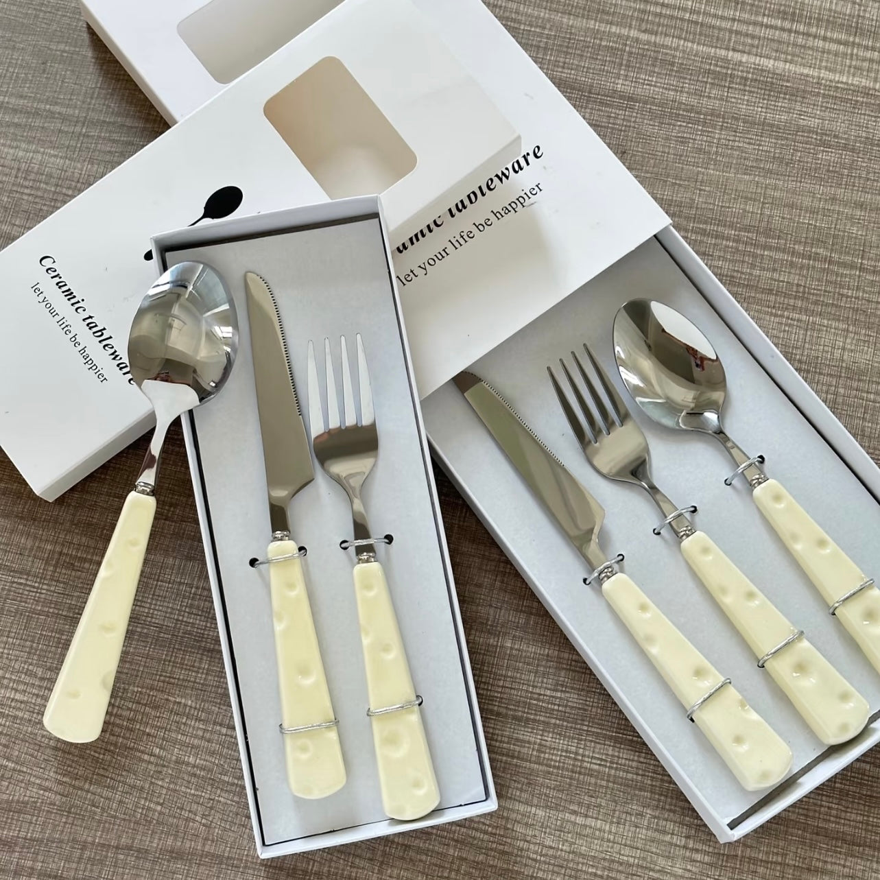 Set of silverware with cream-colored handles in a box on a textured surface
