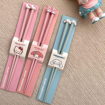 Set of chopsticks with packaging featuring Hello Kitty, My Melody, and Cinnamoroll on a beige surface.