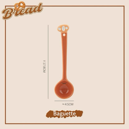 A set of ceramic measuring spoons with cute snack-themed handles, displayed in a kitchen setting.