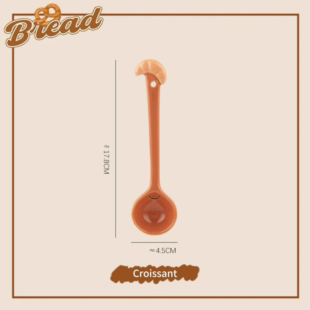 A set of ceramic measuring spoons with cute snack-themed handles, displayed in a kitchen setting.