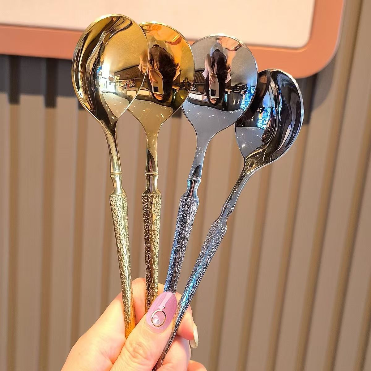 Luxury stainless steel round spoons in gold and silver with intricate textured handles.