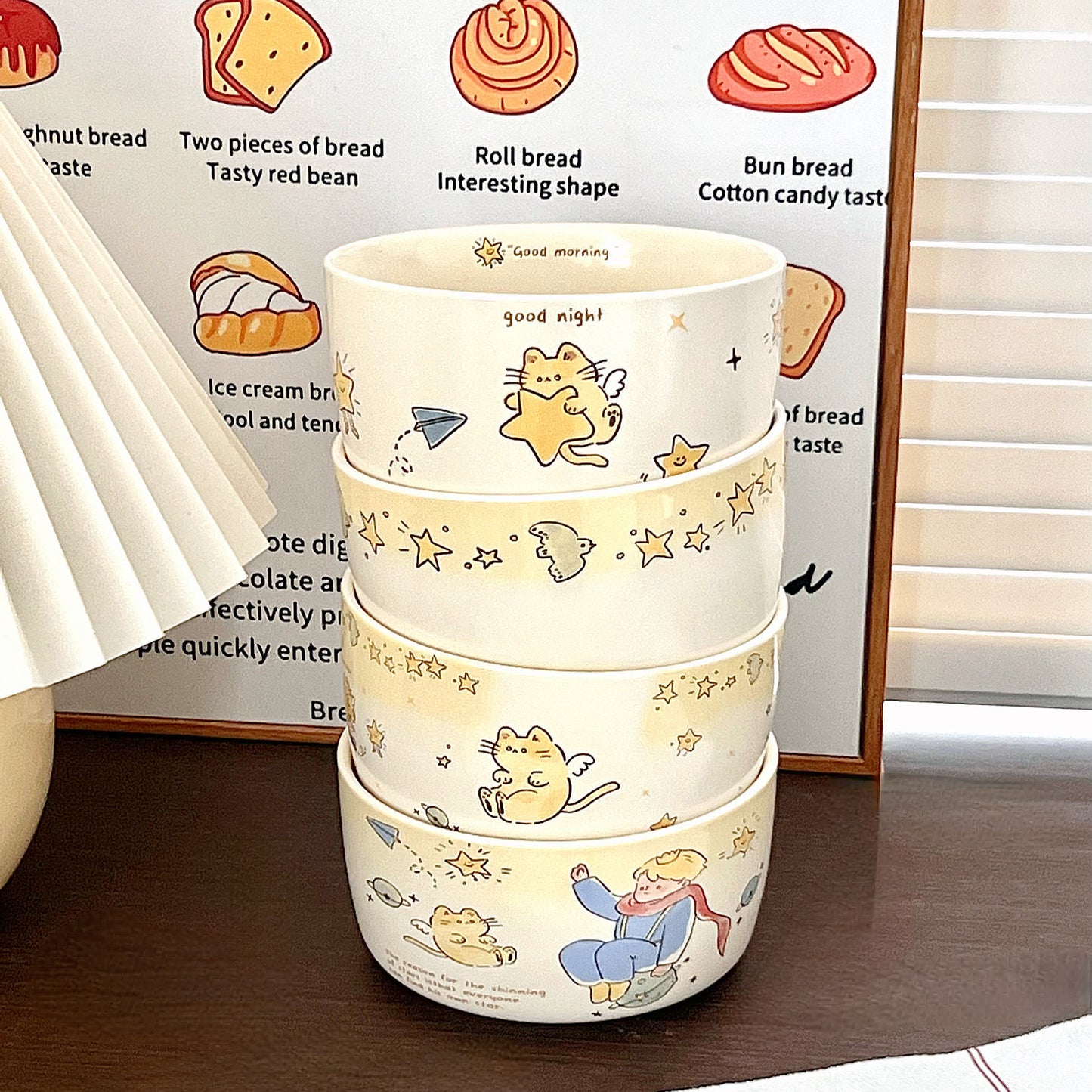 Stack of three ceramic bowls with cartoon designs on a wooden surface.