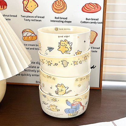 Stack of three ceramic bowls with cartoon designs on a wooden surface.
