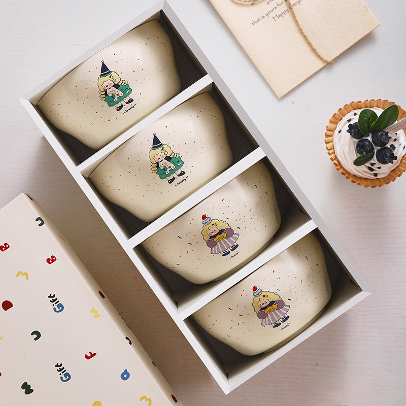 Set of four ceramic bowls with cartoon character illustrations in a box, with a cupcake on the side.