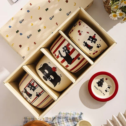 Set of ceramic dog bowls with cute designs in a gift box on a light surface.