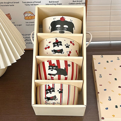 Set of ceramic bowls with dog designs in a box on a wooden surface.