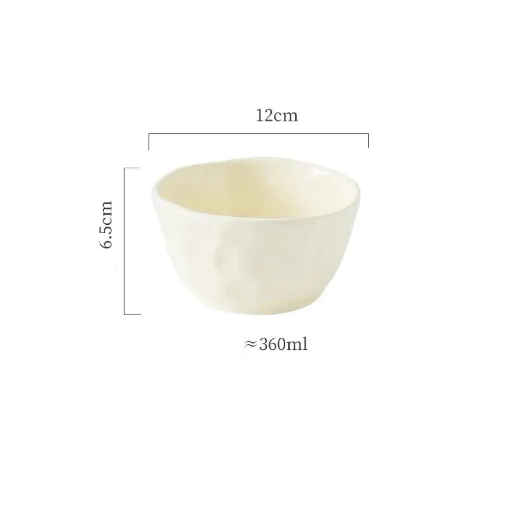 A set of textured ceramic bowls in beige and green colors, stacked on top of each other on a dining table.