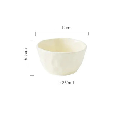 A set of textured ceramic bowls in beige and green colors, stacked on top of each other on a dining table.