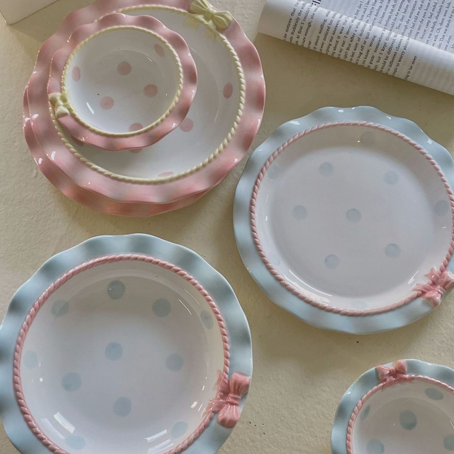 Set of ceramic plates with pink and blue polka dot patterns on a light surface.