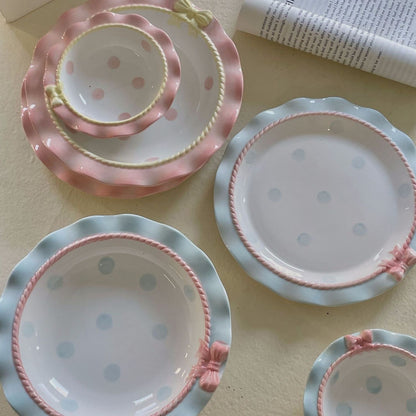 Set of ceramic plates with pink and blue polka dot patterns on a light surface.