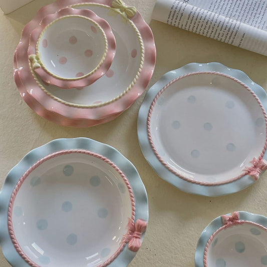 Set of ceramic plates with pink and blue polka dot patterns on a light surface.