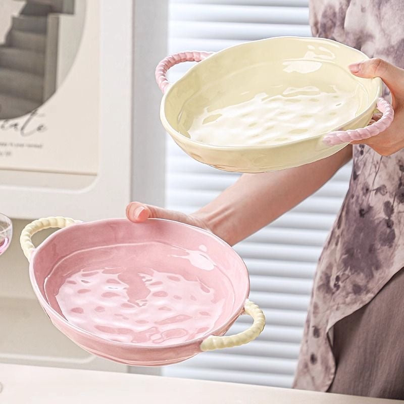 Person holding two ceramic bowls, one yellow and one pink, in a home setting.