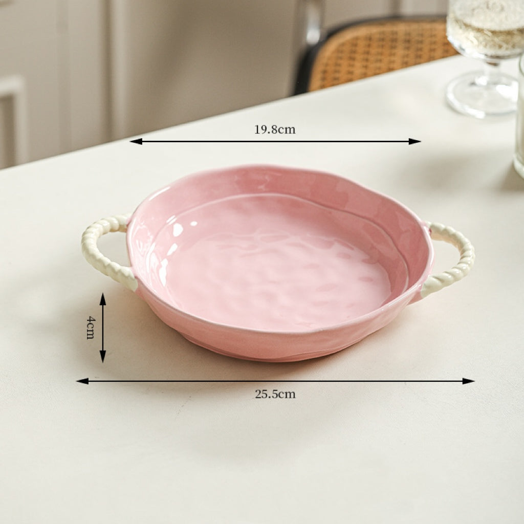 Pink ceramic dish with handles on a white surface, showing measurements.