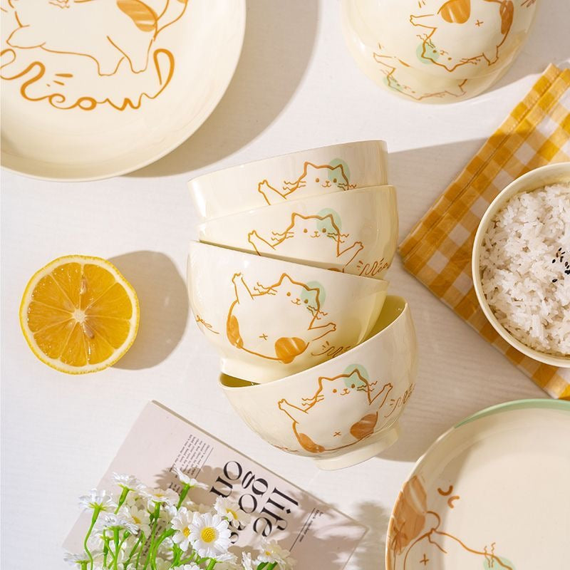 Ceramic bowl and plate set featuring playful cat illustrations on a bright dining setup.