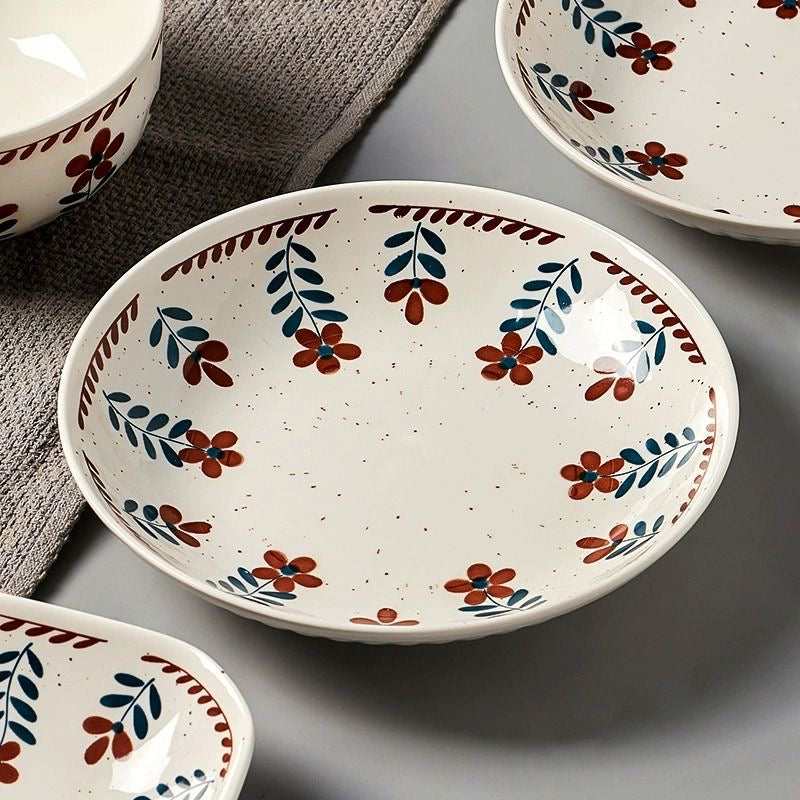 Rustic floral ceramic plate set with hand-painted design placed on a wooden cutting board.