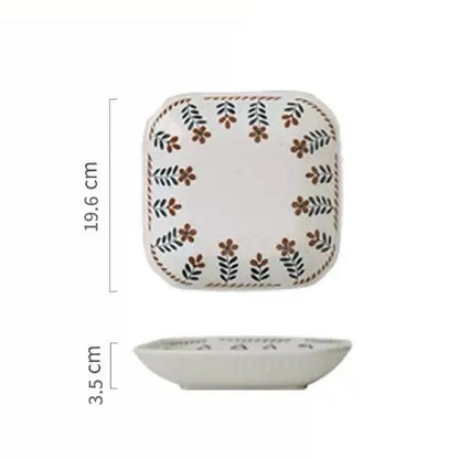 A ceramic bowl with hand-painted floral designs in warm earthy tones on a white background, alongside parts of other bowls and plates.