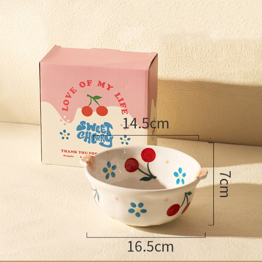 Ceramic bowl with cherry design and packaging box on a beige background