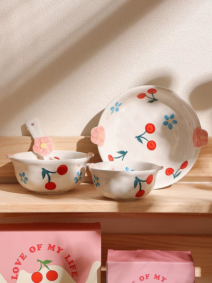Ceramic tableware set with cherry design on a wooden surface