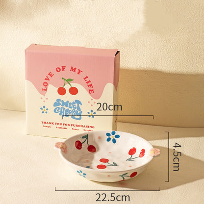 Ceramic plate with cherry design next to its packaging on a beige background