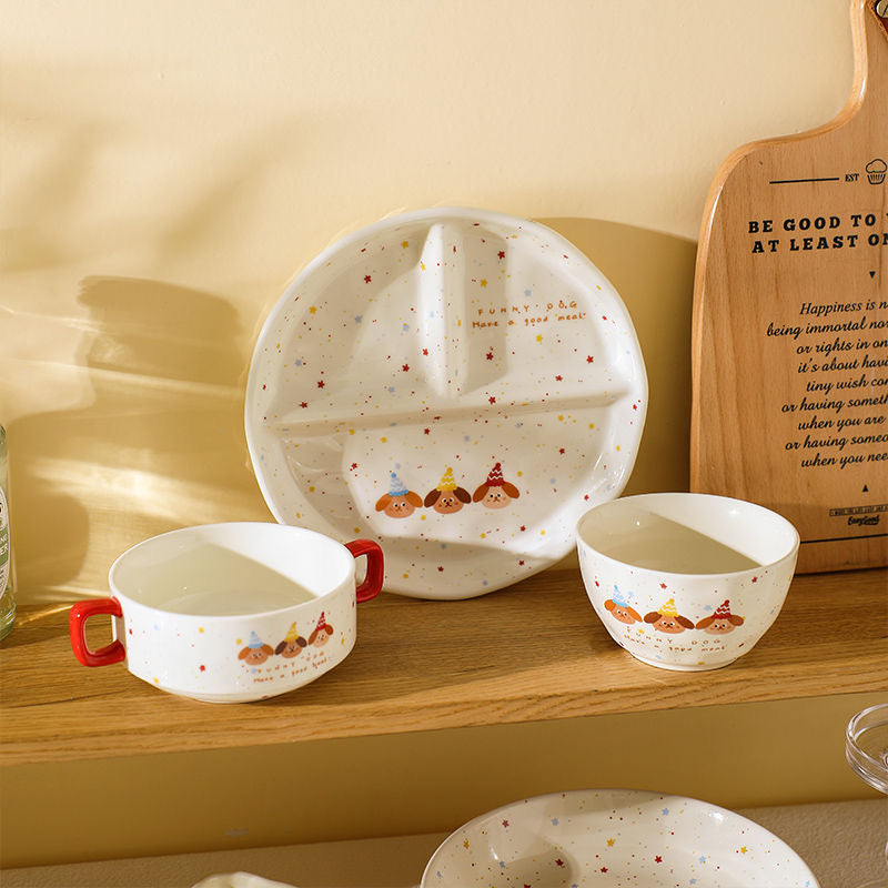 Children's ceramic tableware set with cartoon design on a wooden shelf.