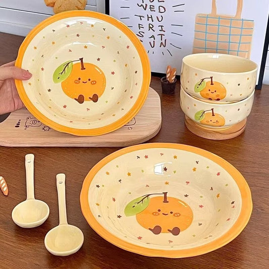 Ceramic dishes with cartoon orange design on a wooden surface
