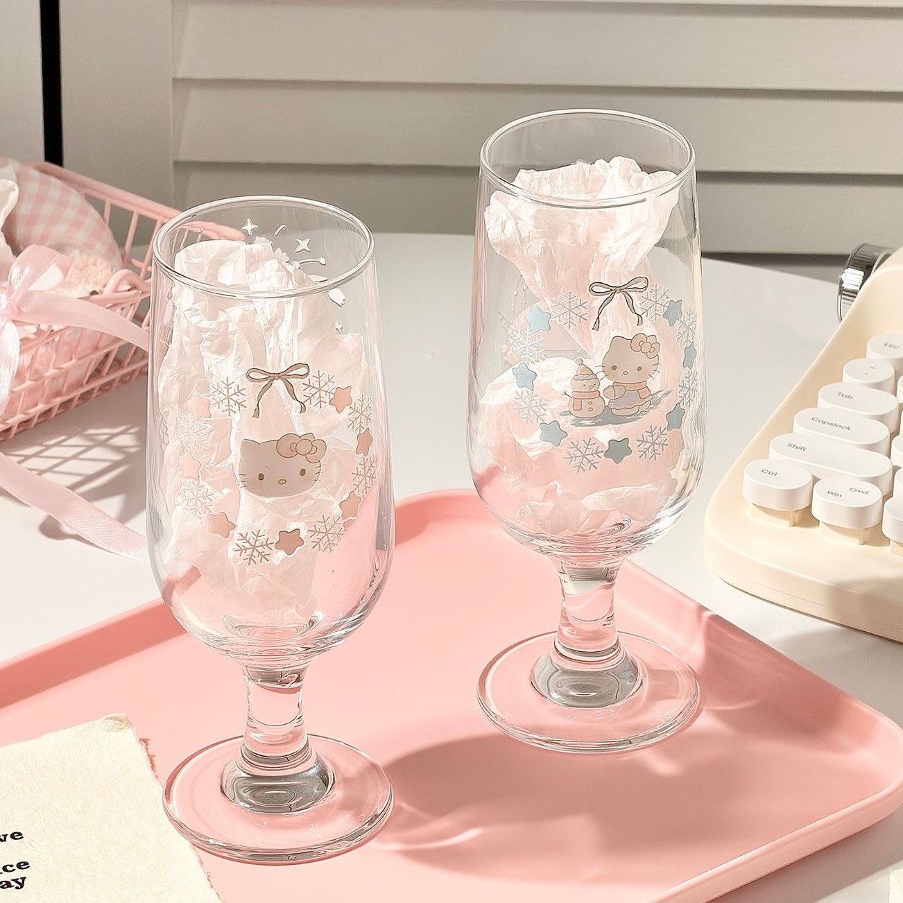 Two decorative glass tumblers with cartoon character design on a pink tray.