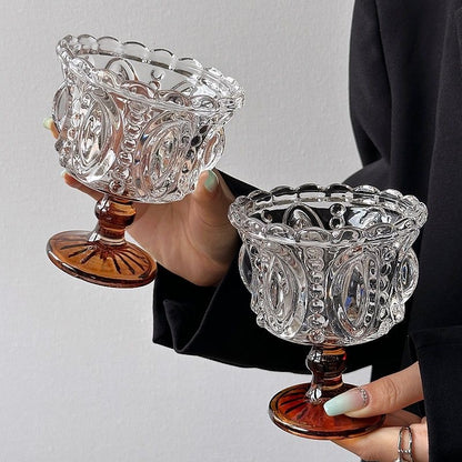 Two ornate glass dishes held by a person against a plain background