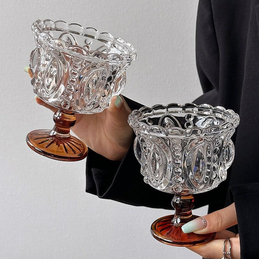 Two ornate glass dishes held by a person against a plain background