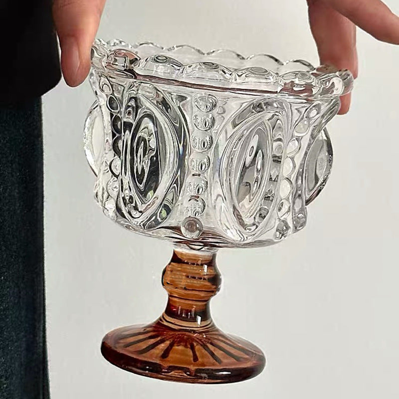 Decorative glass bowl with a wooden base held by two hands against a neutral background