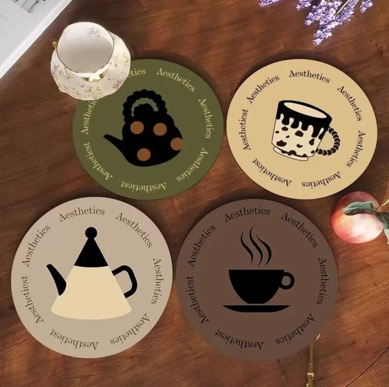 Four coasters with teapot and coffee cup designs on a wooden surface.