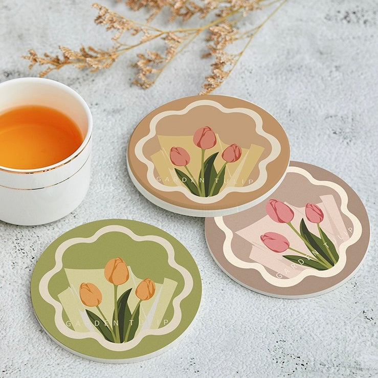 Set of three floral coasters with a cup of tea on a light surface.