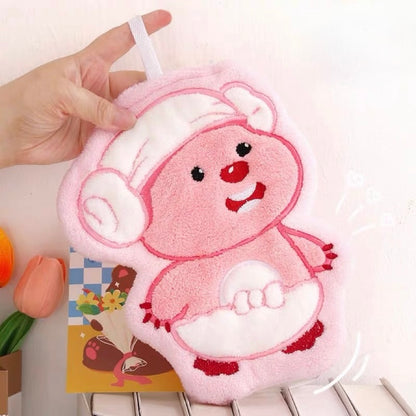 Loopy plush toy held by a hand on a white surface with a colorful card in the background.