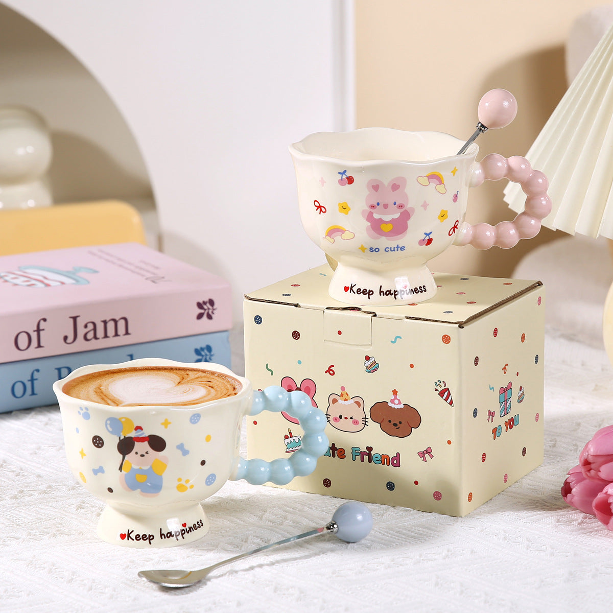 Two cartoon-themed ceramic cups with a box in the background