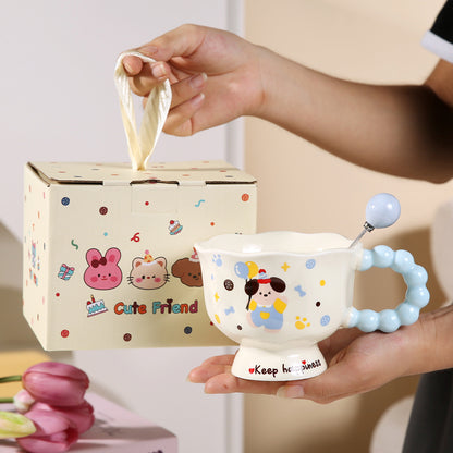 Cute cartoon-themed cup with a teething ring held by a hand, next to a tissue box with cartoon characters.