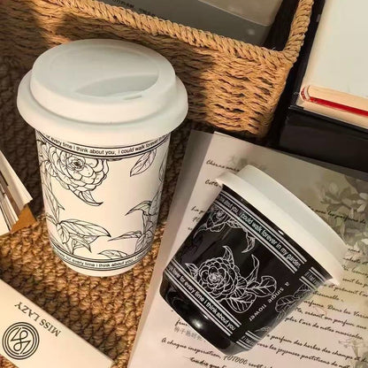 White travel mug with black floral design on a textured surface