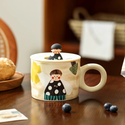 Two ceramic mugs with hand-drawn illustrations of cute couples, one wearing a green dress and the other in a black suit, displayed on a table.