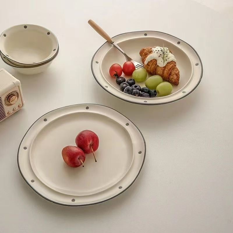 Two ceramic plates with fruit and a croissant on a light surface.